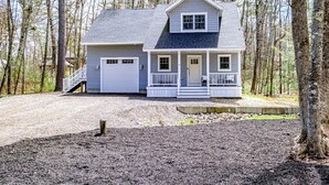 Ein zweistöckiges Haus mit Veranda, Garage und Auffahrt.