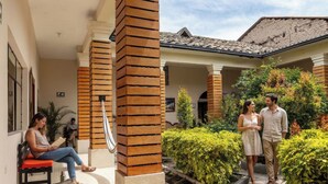 A building with a covered patio, wooden columns, and a pathway leading to a door. - Back Packer (Ibarra)