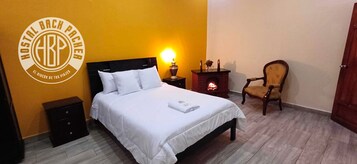 Una habitación de hotel con cama, mesita de noche, sillón y chimenea.