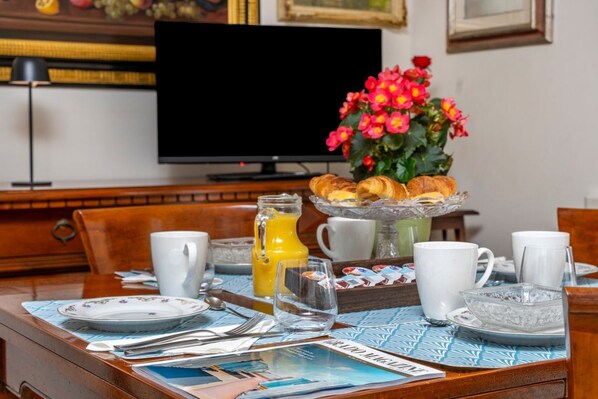 A breakfast table with plates, cups, a pitcher of orange juice, and a vase of flowers.