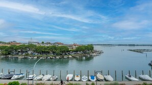 A marina with boats docked, a cyclist, and houses in the background. - GuestHost - Relais Rosanna Stunning Lagoon-View Apartment (Grado)