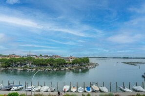 A marina with boats docked, a cyclist, and houses in the background. - GuestHost - Relais Rosanna Stunning Lagoon-View Apartment (Grado)