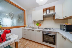 A kitchen with a stove, oven, microwave, and a window with frosted glass. - Spacious 80m2 apartment located on the third floor of a building with a lift (NOT suitable for disabled people). A step to access it.Ideal for 5 people.Equipped with two balconies with splendid views of the lagoon, it offers a relaxing and panoramic stay (Grado)