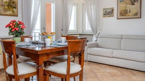 A dining area with a wooden table, chairs, and a vase of flowers. - GuestHost - Relais Rosanna Stunning Lagoon-View Apartment (Grado)