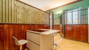 Ein Zimmer mit Holzwandverkleidung, einer weißen Küchenzeile und einer Glastür, die nach draußen führt.