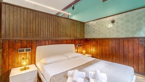 Ein Hotelzimmer mit einer holzverkleideten Wand, einem Bett mit weißen Leinen, zwei Nachttischen mit Lampen.