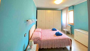 Une chambre à coucher comprenant un lit, une table de chevet, une armoire, une fenêtre et une chaise.