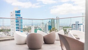 A modern balcony with white, curved seating and a cityscape view.