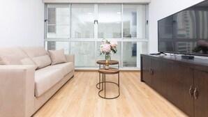Una sala de estar moderna con un sofá, televisor, mueble y ventana con vistas.