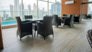 Ein moderner Konferenzraum mit großen Fenstern, Korbmöbeln und Blick auf die Stadt.
