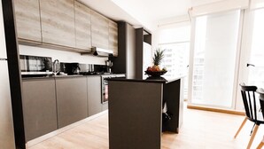 A modern kitchen with grey cabinets, a black island, and a dining area with a black chair.