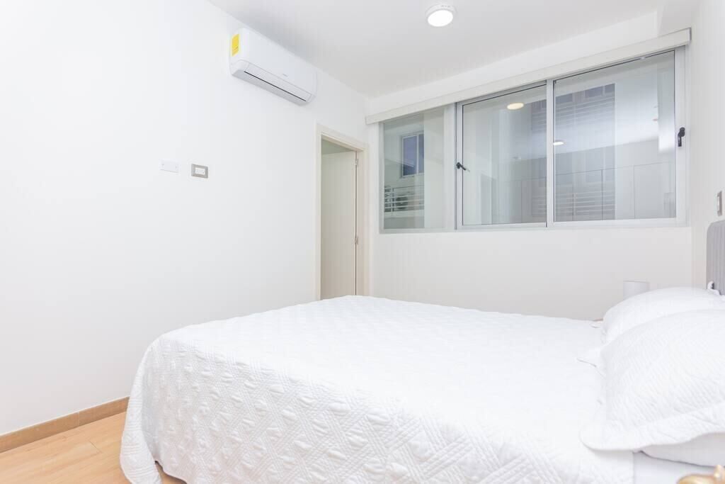 A bedroom with a bed, a window, and an air conditioning unit.