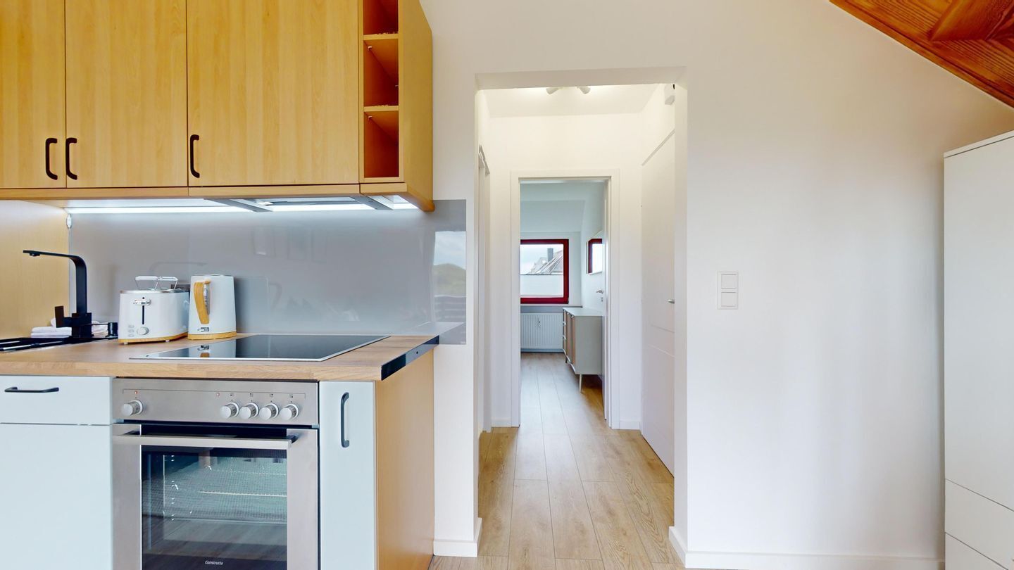 Une cuisine moderne avec des meubles en bois, un four encastré et un plan de travail équipé d’appareils électroménagers.
