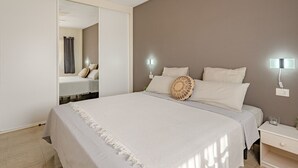 A bedroom with a large bed, a ceiling fan, a wardrobe, and bedside lamps.