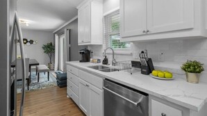 A modern kitchen with white cabinetry, stainless steel appliances, and a countertop with a coffee maker, sink, and fruit bowl. - 3-Bed Haven - 6 pple Hot tub, King bed, Pool & ping pong table, Grill, Fire pit (Richardson)