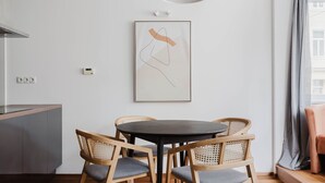 Moderni keittiö, jossa on pyöreä ruokapöytä, puutuolit ja riippuvalaisin.