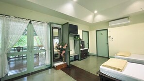 A room with a bed, a TV, a desk, and a window with curtains.