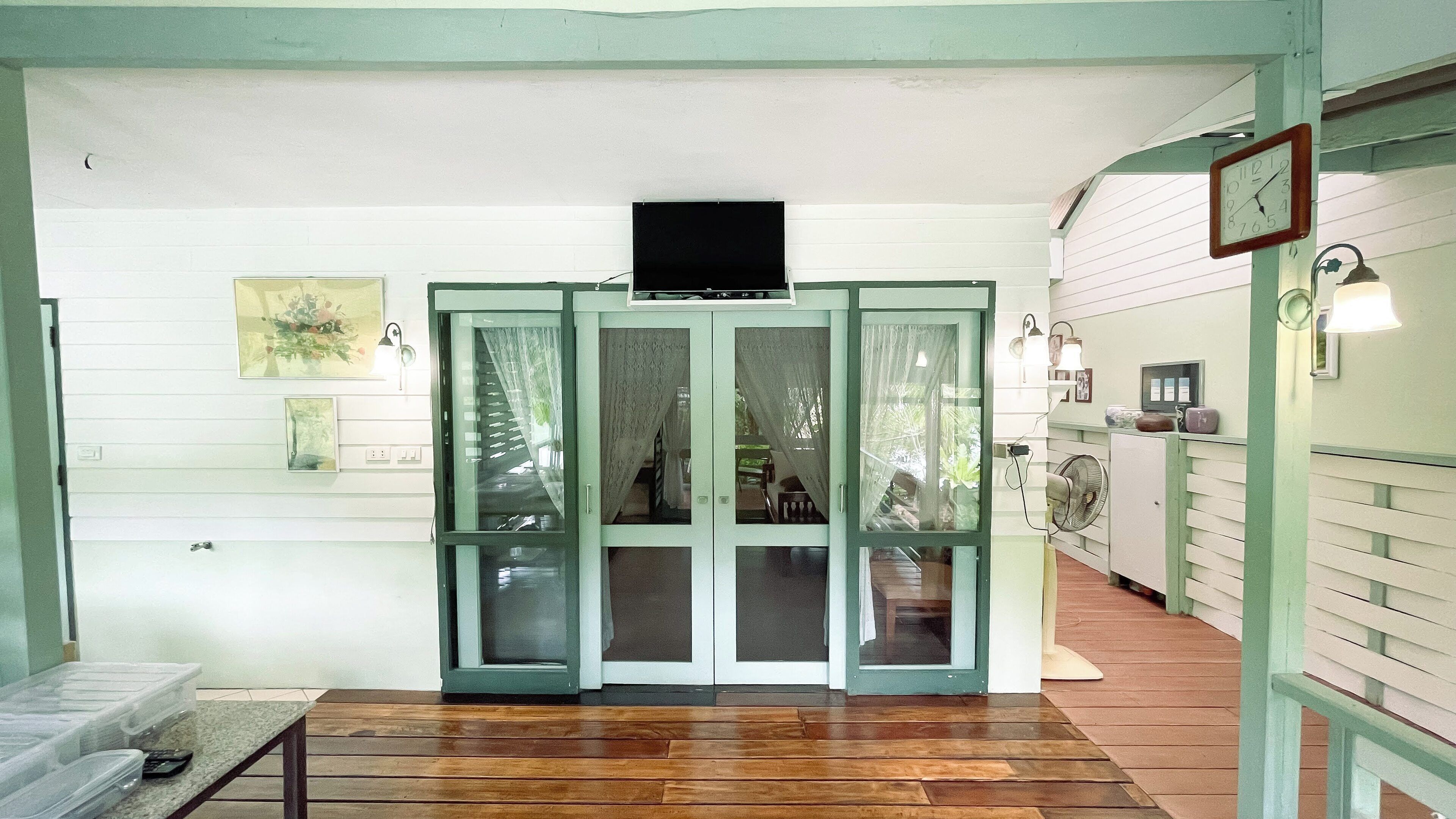 A room with a wooden floor, a bench, a TV on a stand, and a door with glass panels.