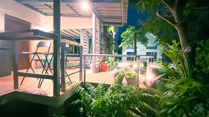 An outdoor patio area with a wooden deck, metal railing, and potted plants.