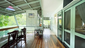 A covered outdoor area with a wooden deck, a table with chairs, and a hanging light fixture. - Rimsira (Pathio)