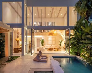 A modern house with a pool, glass doors, and a dining area. - Villa Belga (Canggu)