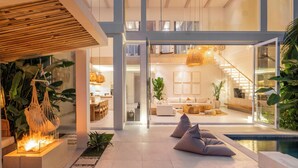 A modern interior with a central open space, a staircase, and a pool area. - Villa Belga (Canggu)