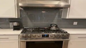 A kitchen with a stainless steel stove, oven, and a kettle on the stove.