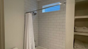 A bathroom with a toilet, a shower with a curtain, and a bathtub.
