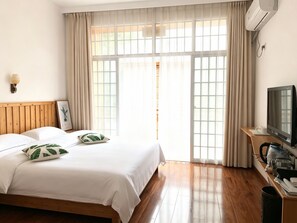 A hotel room with a bed, a television, a coffee maker, and a window with curtains.