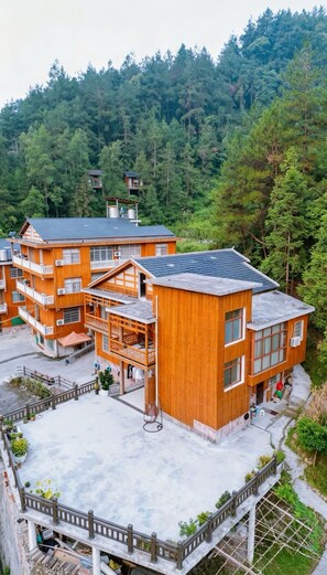 A multi-story wooden building with balconies, surrounded by a forested area. - Tongfu Inn - In the National Park - English Service - Free Tour - Itinerary Planning - Reverse Route Sightseeing with Almost No Queues (Zhangjiajie)