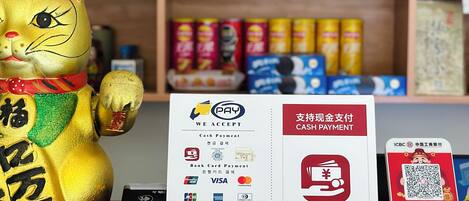 A golden cat figurine, a payment acceptance sign, and a QR code on a table.