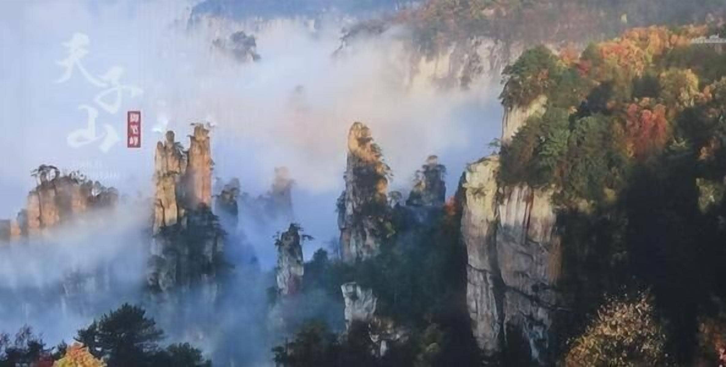 A mountainous landscape with rocky cliffs and dense forest.