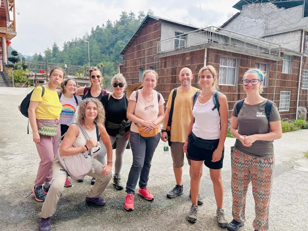 Un groupe de personnes se tient devant un bâtiment rustique doté d’un balcon.