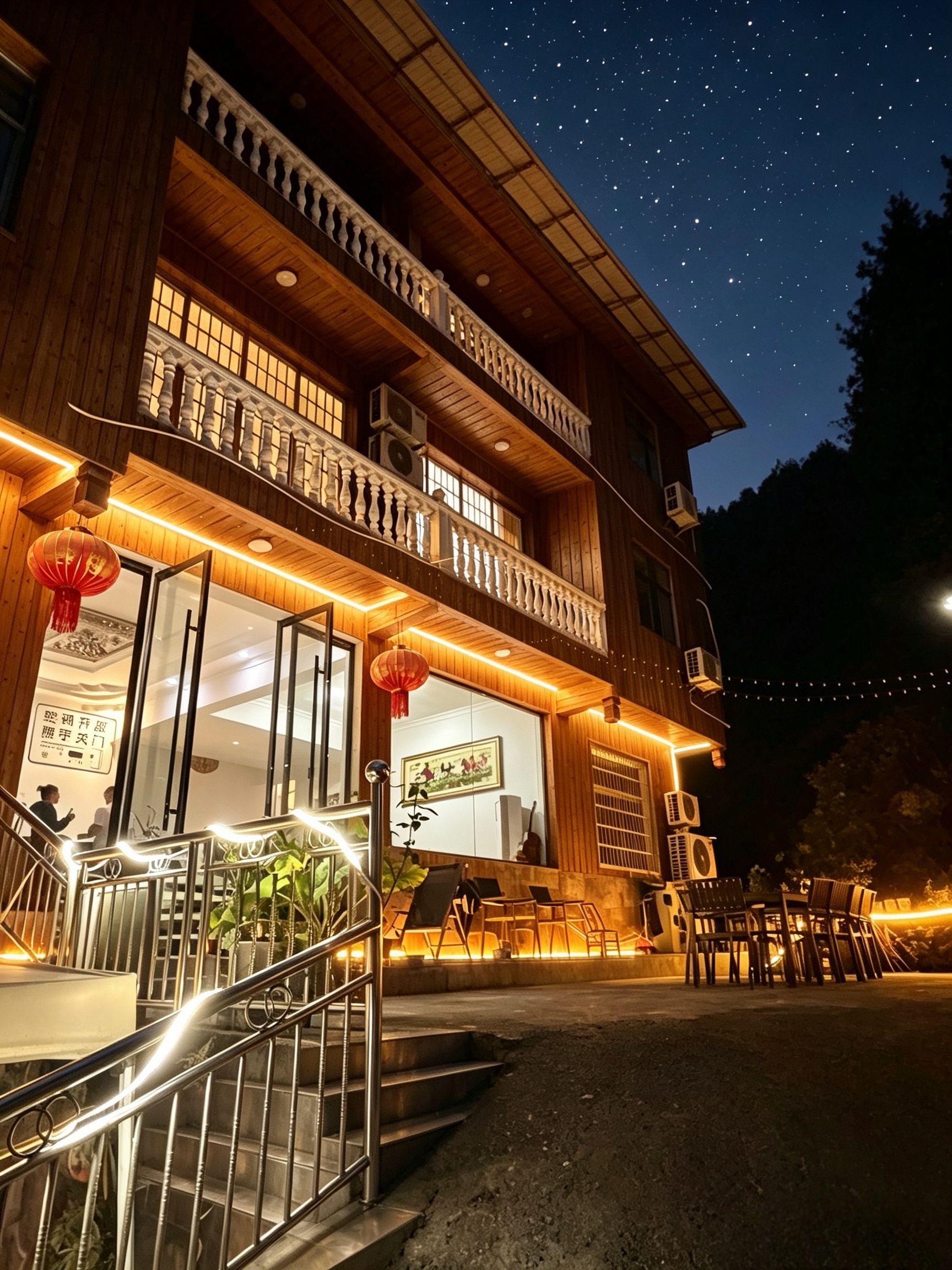 A two-story building with a balcony, outdoor seating, and a view of the night sky.