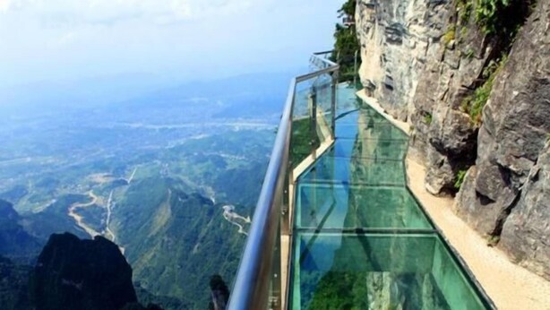 Eine Glasgangway mit Metallgeländer mit Blick auf eine Berglandschaft.