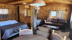 A cabin with two beds, a sofa, a table, and a hanging lamp. - Winmar Cabins (Twin Lakes)