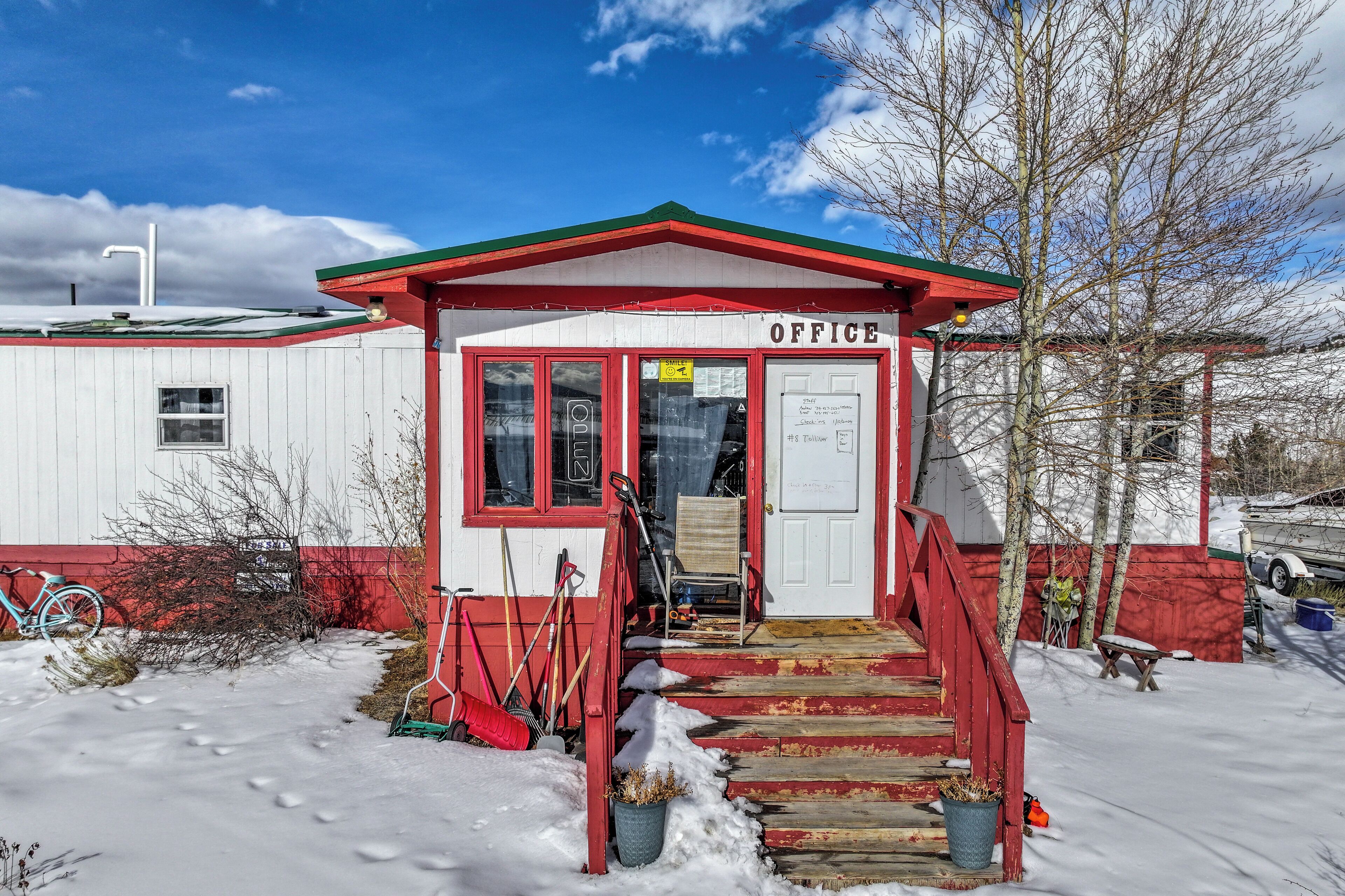 A small office building with a red and white exterior, a wooden staircase leading to the entrance, and a snow-covered ground.