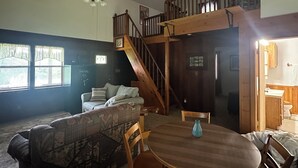Un salon confortable avec un canapé, une table à manger et un escalier menant à l’étage supérieur.