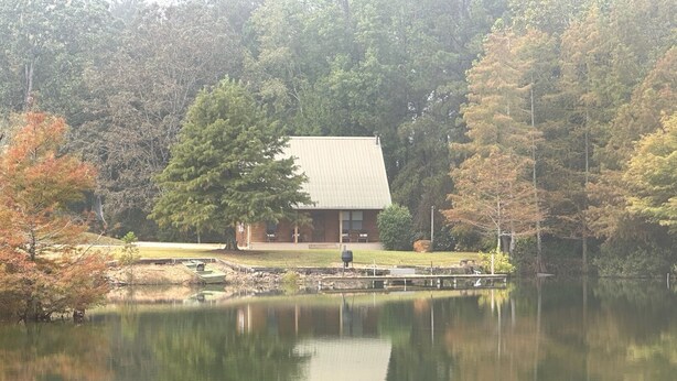 Un chalet au bord du lac, doté d’un quai, entouré d’arbres et bordé d’une zone herbeuse.
