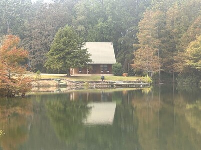 Cozy Cabin setting behind a 1 1/2 acre pond that is lined with Cypress Trees.