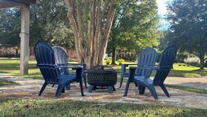 Une terrasse avec des fauteuils Adirondack et un foyer extérieur.
