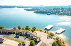 Luftaufnahme eines Hotels mit Parkplatz, einem Steg und einem See.