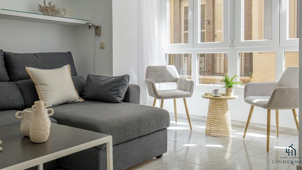 A modern living room with a grey sofa, two armchairs, a coffee table, and a small side table with a plant.