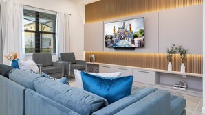 Ein modernes Wohnzimmer mit einem großen Flachbildfernseher an der Wand, grauen Sofas und einer Wand als Holzdekor.