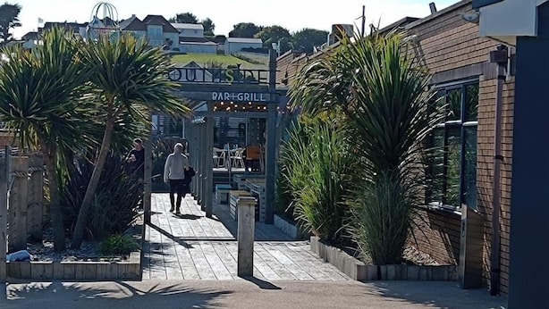A wooden pathway leading to a bar and grill with a sign above it. - Sleeps 6, Pets Allowed & Free Parking (Weymouth)