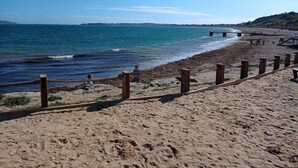 A sandy beach with a wooden fence and a pier extending into the water. - Sleeps 6, Pets Allowed & Free Parking (Weymouth)