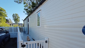 A mobile home with a fenced porch and a dog standing by the gate. - Sleeps 6, Pets Allowed & Free Parking (Weymouth)