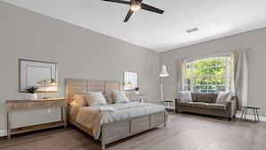 A bedroom with a bed, a sofa, a desk, and a window with curtains.