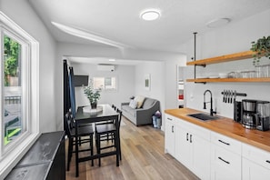 A modern kitchen with white cabinets, a wooden countertop, and a built-in sink. - Charming Riverside Suite | Kitchenette, BBQ, Dock (Lake Cowichan)