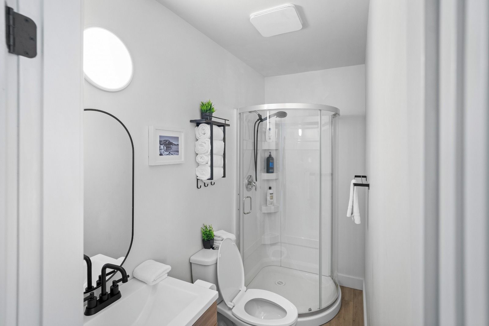 Une salle de bain moderne avec une douche à parois de verre, des toilettes, un lavabo et un miroir.